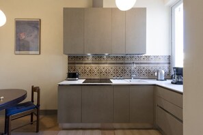Una cucina compatta con un'isola centrale, forno a incasso e macchina per il caffè.