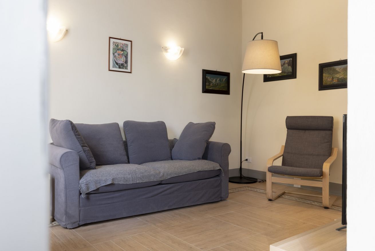 A living room with a grey sofa, a wooden chair, and a floor lamp.