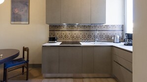 Una cuina compacta amb una illa central, forn integrat i cafetera.