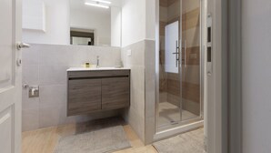 Un bany modern amb una cabina de dutxa de vidre, un moble de tocador de fusta i un mirall gran.