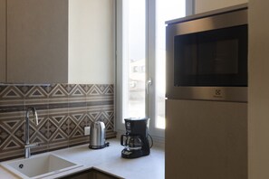 A modern kitchen with a stainless steel sink, a kettle, a coffee maker, and a microwave. - Fossi Elegant Apartment (Firenze)