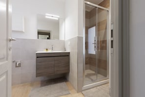 Une salle de bain moderne avec une douche à parois de verre, un meuble-lavabo en bois et un grand miroir.