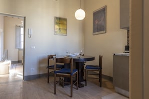 Un coin repas comprenant une table ronde, quatre chaises et deux appliques murales.