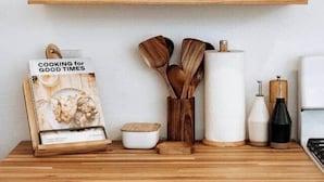 A kitchen counter with a cookbook, wooden utensils, and a rolling pin.