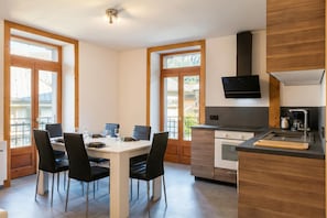 A modern kitchen with a dining area, large windows, and a built-in stove.