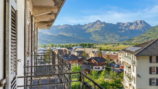 A balcony with a view of a town and mountains.