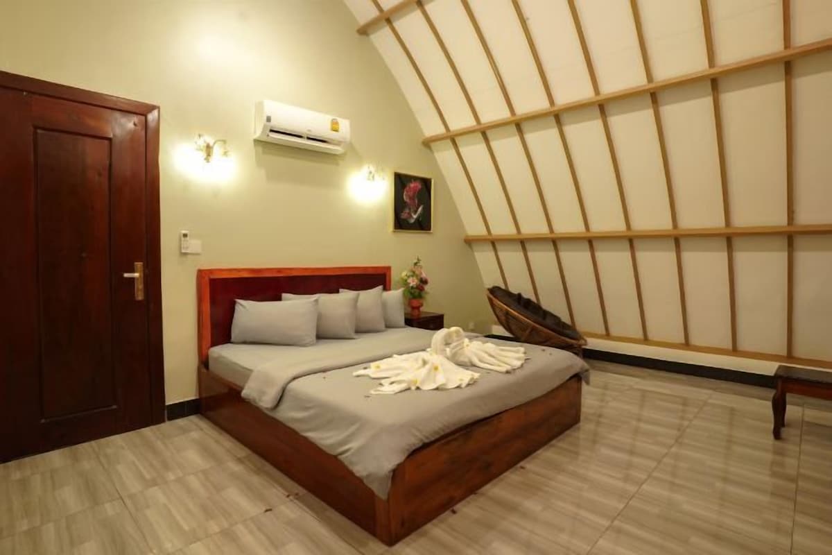 Een slaapkamer met een bed, een houten deur, een airconditioning en een schuine plafond.