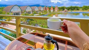 A balcony with a table set for tea, overlooking a pool and resort buildings. - Bali Villa Kampot (Kampot)