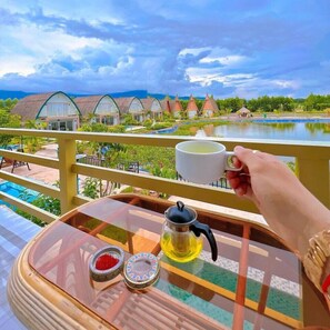 A balcony with a table set for tea, overlooking a pool and resort buildings.