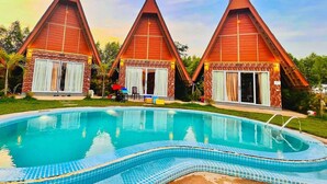 A resort with three conical-roofed cabins and a central swimming pool. - Bali Villa Kampot (Kampot)