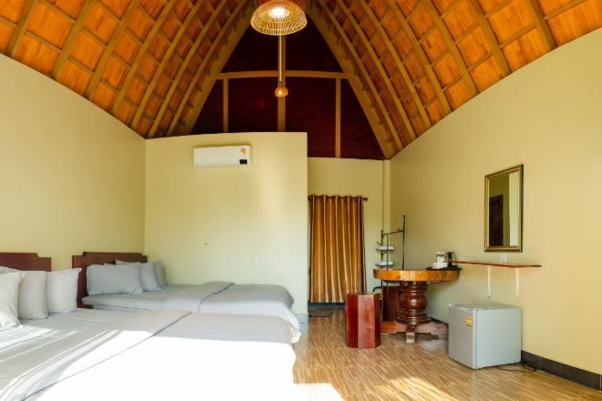 A room with a bed, a desk, a chair, a small refrigerator, and a mirror on the wall.
