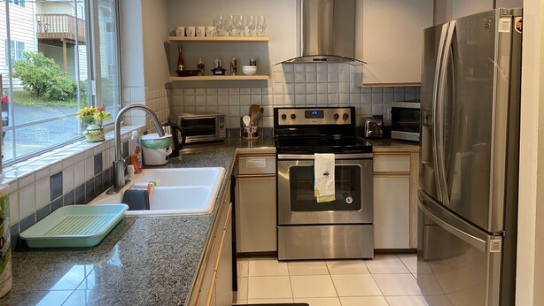 Cozinha moderna com eletrodomésticos de aço inoxidável, uma janela com vista para o exterior e forno embutido.