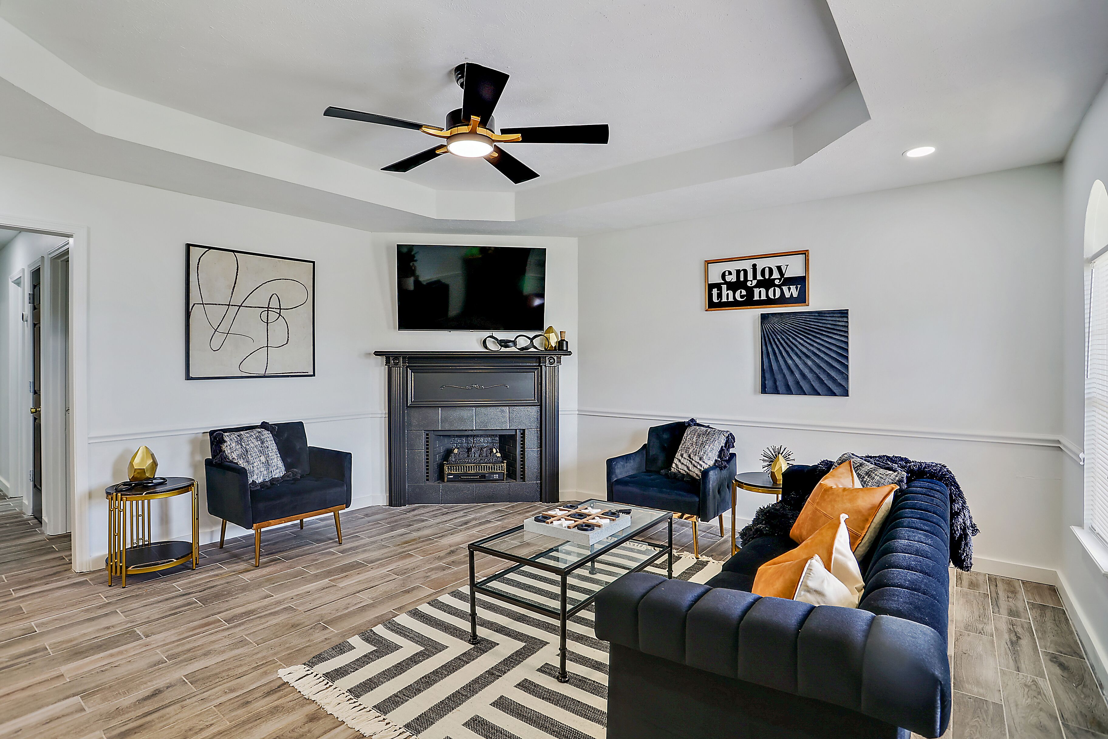 Un salon moderne avec une cheminée, deux canapés, une table basse et un ventilateur de plafond.