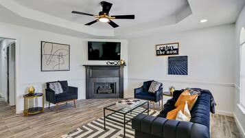 Un salon moderne avec une cheminée, deux canapés, une table basse et un ventilateur de plafond.