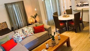 A living room with a sofa, red cushions, a coffee table, and a dining area with a table and chairs. - Villa with outdoor spaces (Cabanas de tavira)