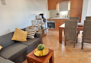 A modern living room with a sofa, a coffee table, and wicker chairs.