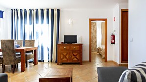 Una sala de estar con un sofá, un mueble de madera, un televisor y un comedor con sillas y una mesa.