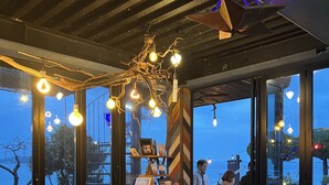 A modern interior with a wooden ceiling, large windows, and a chandelier. - SkyStarSea Pension (Muan)