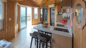 A wooden cabin interior with a kitchen area, including a counter, sink, and stools. - SkyStarSea Pension (Muan)