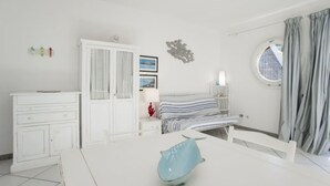 A bedroom with a bed, a dresser, a nightstand, a window with curtains, and a wall decoration.