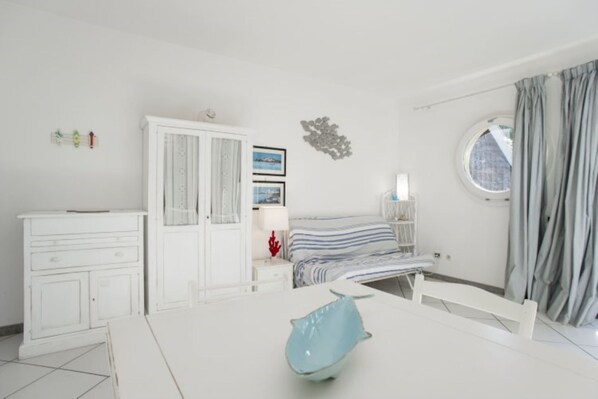 A bedroom with a bed, a dresser, a nightstand, a window with curtains, and a wall decoration.