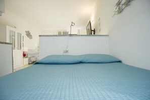 A bedroom with a bed, a desk, a lamp, and a wardrobe.