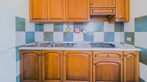A kitchen with wooden cabinets, a stainless steel sink, and a gas stove. - APP.TI STELLA MARINA - STELLA MARINA 3 (Marina di Campo)