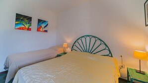 A bedroom with two beds, a green metal headboard, and two wall-mounted paintings. - APP.TI STELLA MARINA - STELLA MARINA 3 (Marina di Campo)