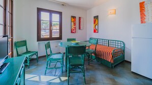 A compact room with a dining table, chairs, a bed, and a refrigerator. - APP.TI STELLA MARINA - STELLA MARINA 3 (Marina di Campo)