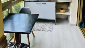 A compact kitchen with white cabinets, a black countertop, and a window overlooking greenery.