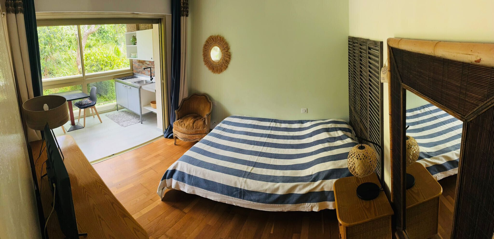 A bedroom with a bed, a chair, a desk, and a view of the outdoors.