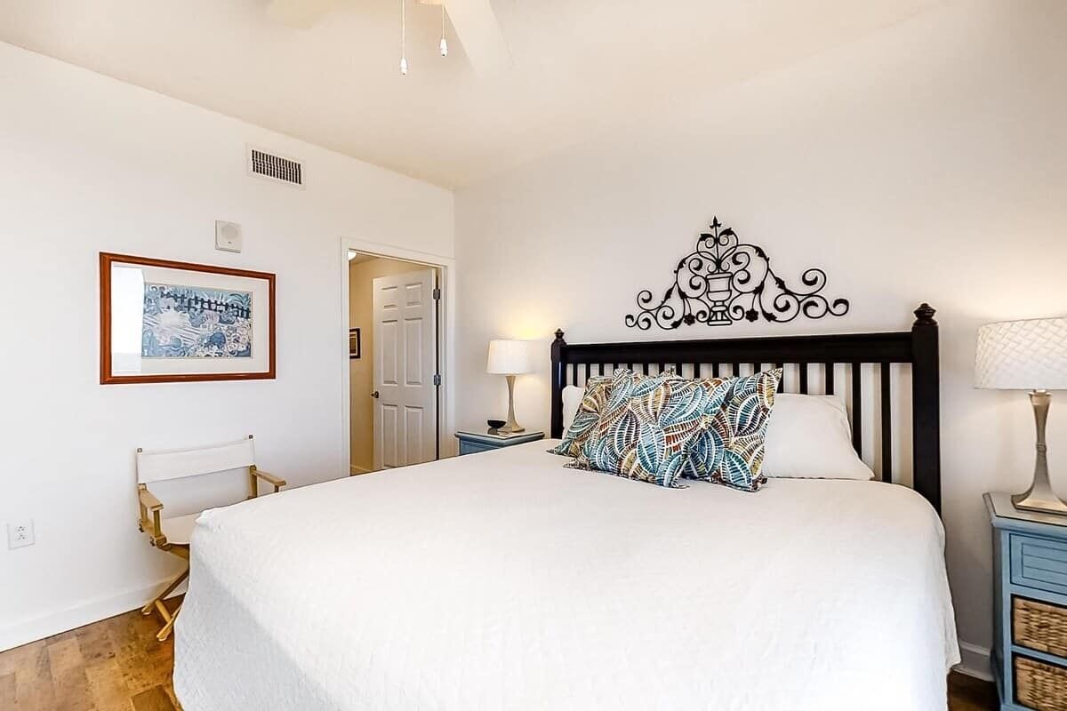 Camera da letto con un letto grande, un quadro appeso al muro, una testiera decorativa e un comodino con una lampada.