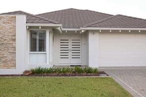 Une maison moderne dotée d’un garage, d’une façade en pierre et d’une pelouse bien entretenue.