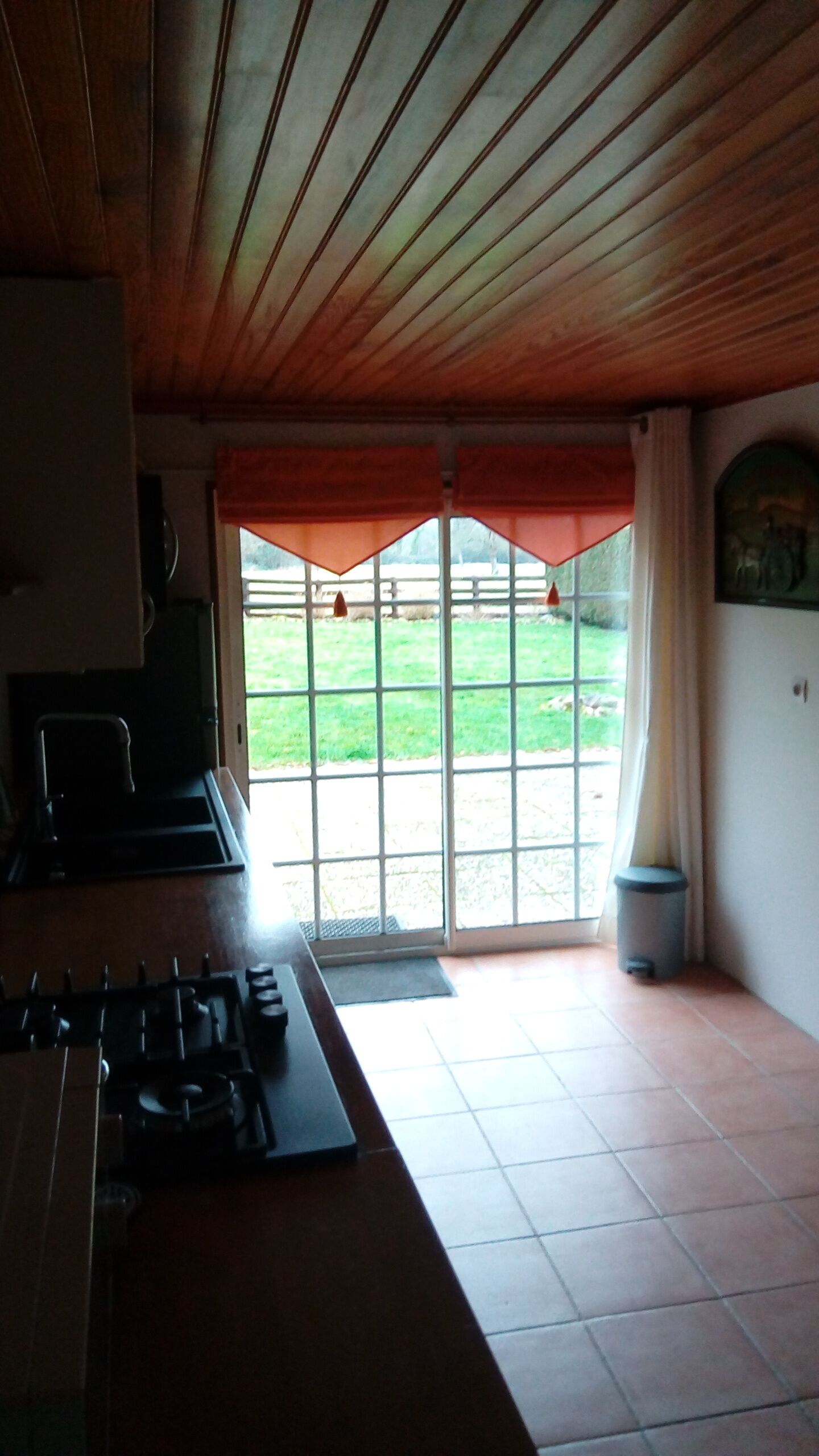 A kitchen with a gas stove, a sink, and a window with a view of a grassy area.