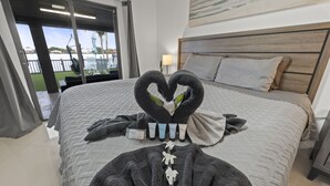 Une chambre d’hôtel avec un lit, une disposition originale des serviettes en forme de cœur et une vue sur l’extérieur.