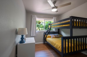 Habitación con literas, ventilador de techo, escritorio con lámpara y ventana con cortinas.