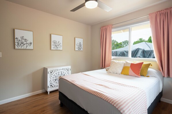Une chambre à coucher comprenant un lit, un ventilateur de plafond et trois œuvres d’art accrochées au mur.
