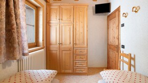 A bedroom with wooden furniture, a window, a radiator, and a television. - Apartment 'Gemma' with Mountain View, Shared Garden and Wi-Fi (Livigno)