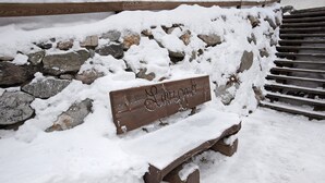 A wooden bench with a sign in front of a stone wall and steps. - Apartment 'Gemma' with Mountain View, Shared Garden and Wi-Fi (Livigno)