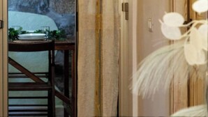 A room with a stone wall, a wooden door, and a table with a plant. - Apartment "Viviana's Holiday Home" with Wi-Fi (TRINITA D'AGULTU E VIGNOLA)