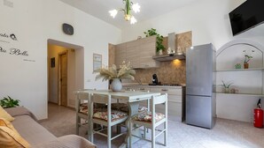 A modern kitchen with a dining table, chairs, a refrigerator, and a TV mounted on the wall. - Apartment "Viviana's Holiday Home" with Wi-Fi (TRINITA D'AGULTU E VIGNOLA)