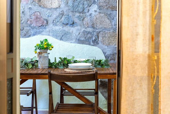 A dining table set with a white plate, a glass, and a vase with green foliage.