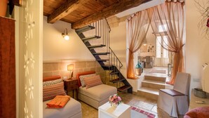 Ein gemütliches Wohnzimmer mit einer Couch, einem Couchtisch, einer Treppe und Blick in die Küche.