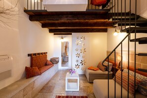 Un salon moderne avec un escalier, une table basse blanche et un canapé agrémenté de coussins à motifs.