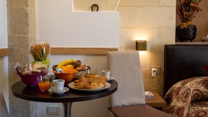 A breakfast table with a variety of food items, a vase with flowers, and a chair.