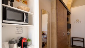 A kitchen with a microwave, coffee maker, and a coffee station.