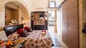 A bedroom with a bed, a desk, a wardrobe, and a view of the outside.