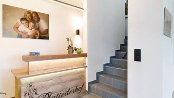 Ein Empfangstresen mit Holzoptik und einem Schild mit der Aufschrift 'Plattiederhof'.