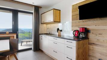 Eine moderne Küche mit großem Fenster, Holzschränken, einem Einbauofen und einer Kaffeemaschine.