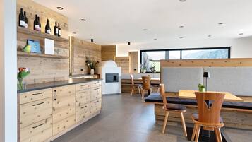 Eine moderne Küche mit Holzausstattung, einem integrierten Weinkühlschrank und einem Essbereich mit Holzstühlen und einer Bank.